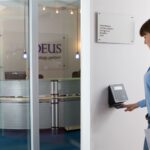 Choosing The Right Device For Each Site Type: What You Need To Know 12 Choosing right device each site type: employee using a wall-mounted biometric attendance device in an office