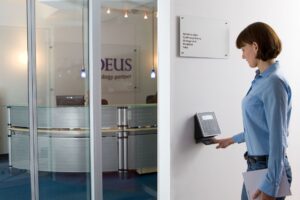 Choosing right device each site type: employee using a wall-mounted biometric attendance device in an office