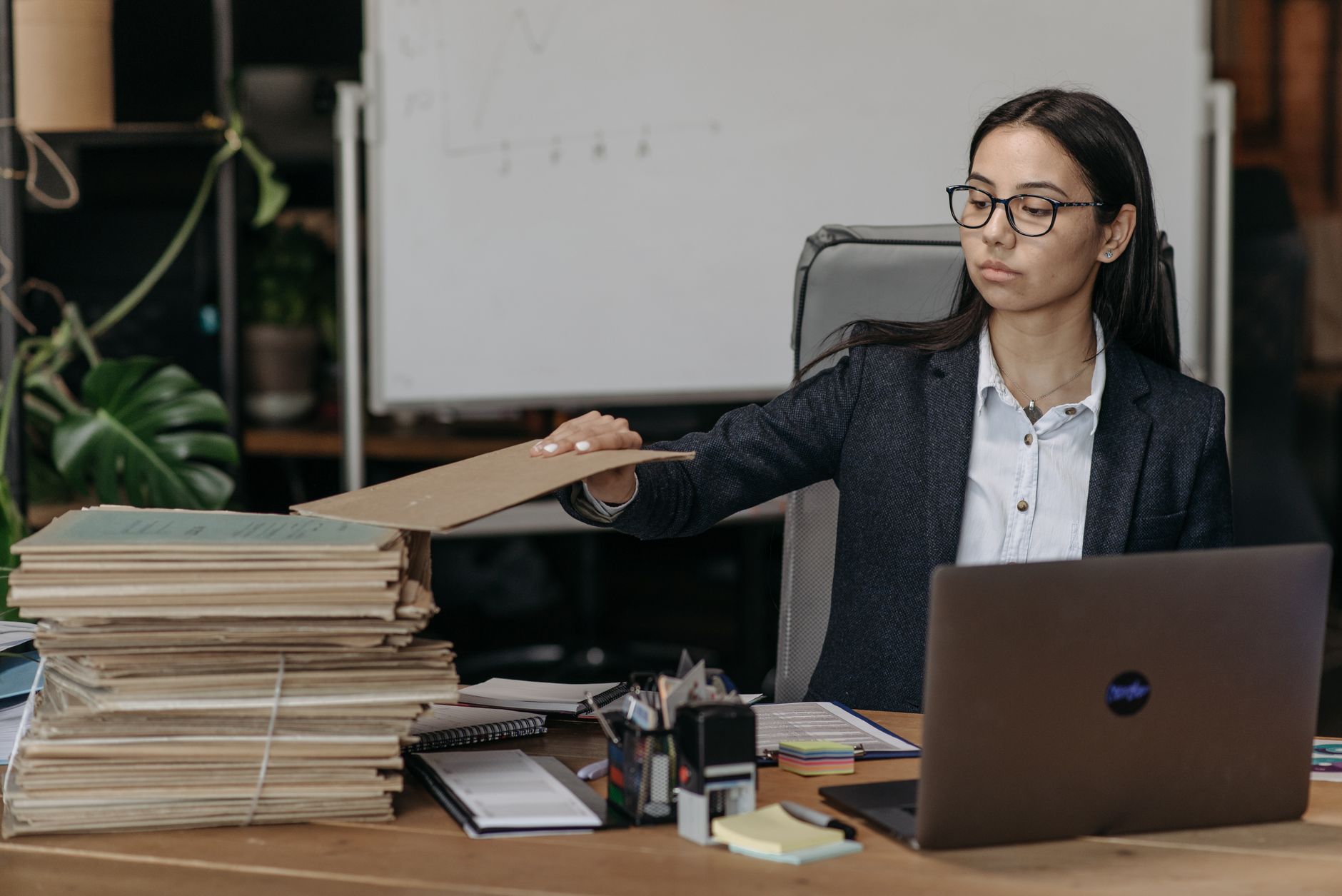 hr team buried admin reclaim hours: an HR officer sorting stacks of paper files beside a laptop