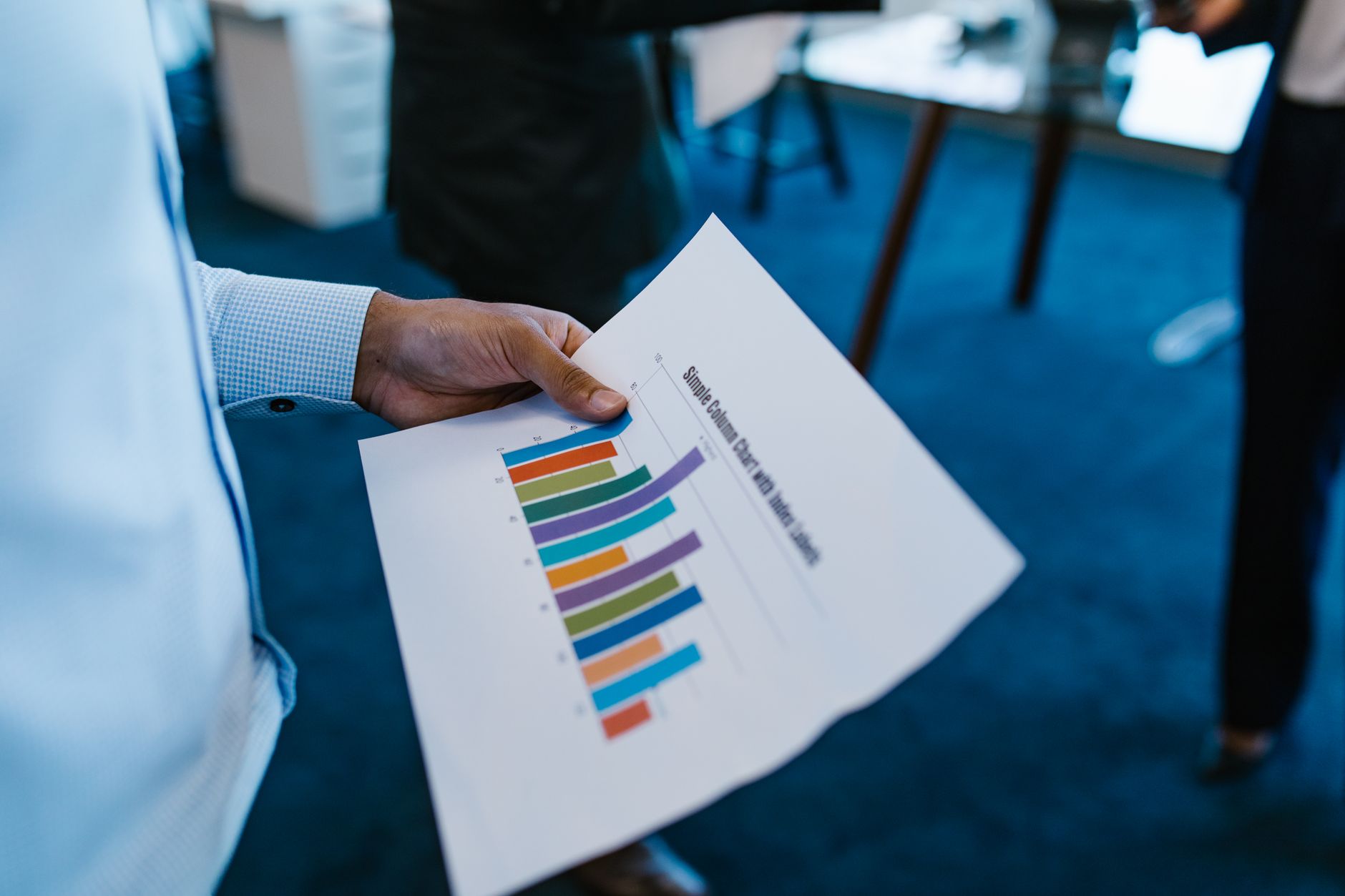 kpis metrics hr manager should track: HR manager reviewing a bar chart KPI report in an office
